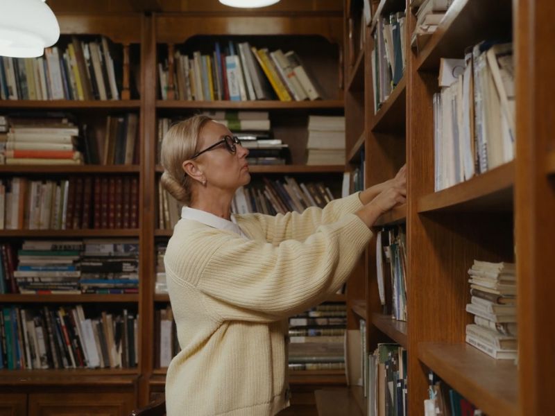 žena bira knjigu u biblioteci