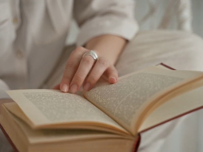 devojka sedi na krevetu i čita knjigu